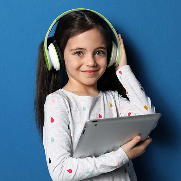Smiling girl wearing headphones and playing on tablet